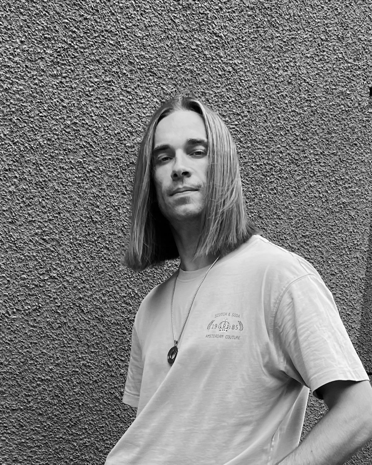 Black and white portrait of Edgar standing against a textured wall